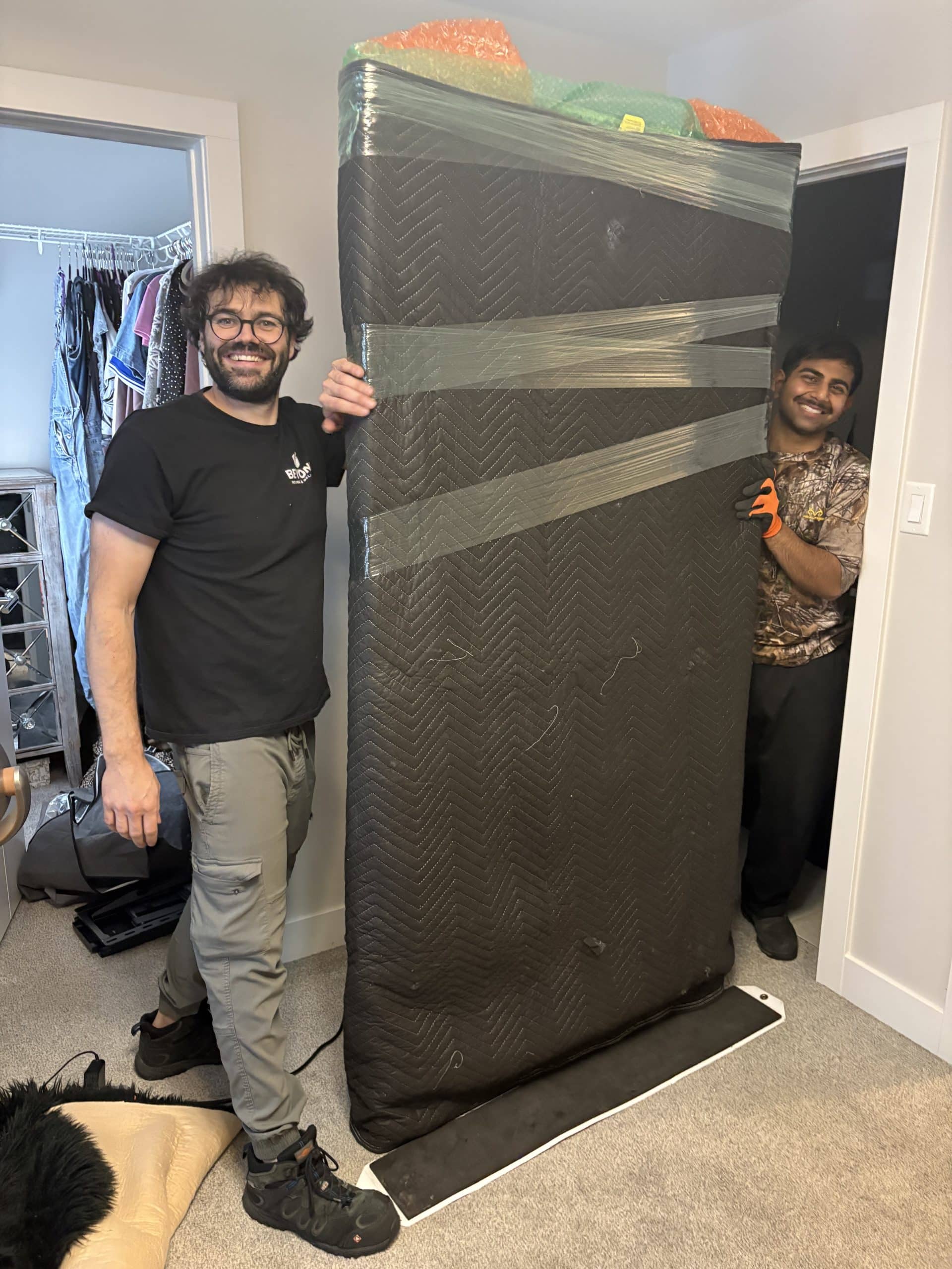 Beyond Moving crew holding a protected mattress safely